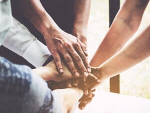 group of inpatient treatment patients joining hands to support one another